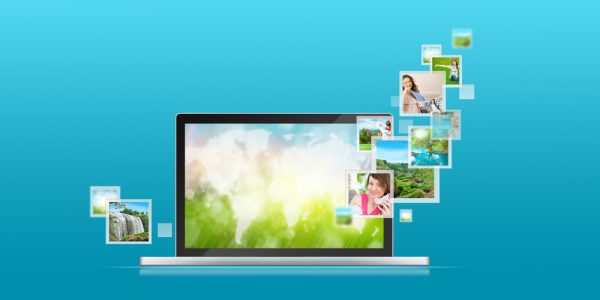 Open laptop at blue background. Pictures are flying out of the screen