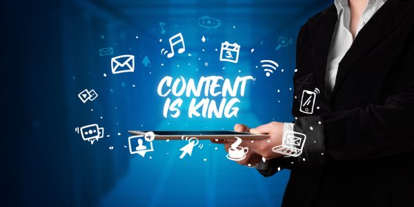 Young business person working on tablet and shows the inscription: CONTENT IS KING